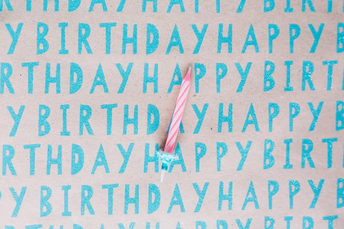 Eine einzelne gestreifte Kerze auf Happy-Birthday-Papier